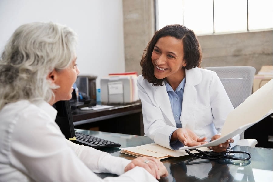 Médecin parlant avec une patiente âgée souriante dans un bureau