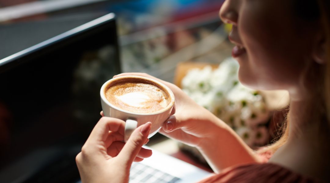 femme tenant entre ses mains une tasse de café latte chaud