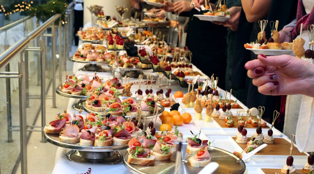 Un buffet somptueux avec divers amuse-bouches, incluant viandes, fromages, fruits et garnitures décoratives, lors d’un événement