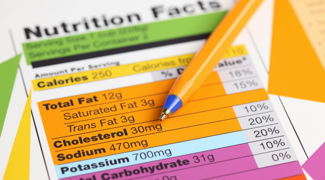 Gros plan sur une étiquette de valeurs nutritionnelles colorée avec un stylo jaune placé en diagonale dessus