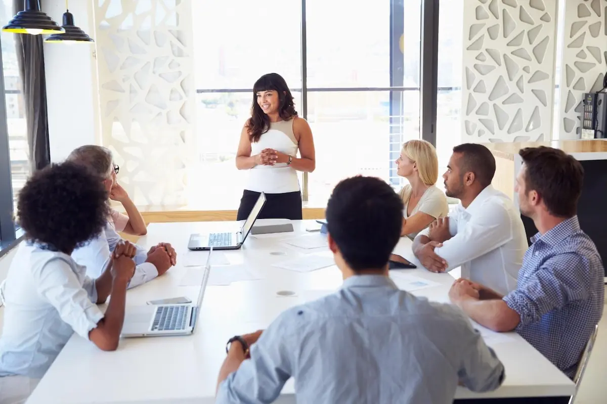 Une nutritionniste donne une présentation à des employés assis autour d'une table | A dietitian presenting to employees seated around a table