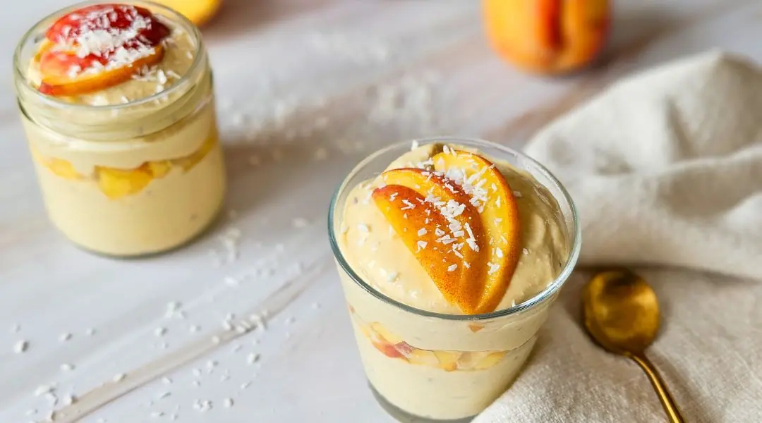 Verrines de mousse aux pêches et mangues, garnies de tranches de pêches fraîches et de noix de coco râpée