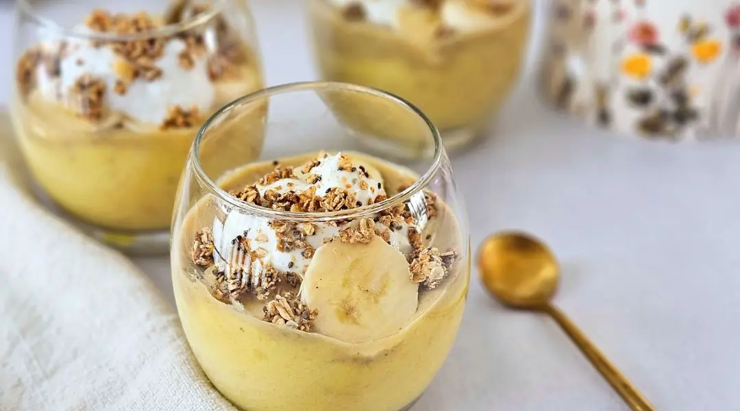 Pouding à la banane dans un verre, garni de granola et tranches de banane