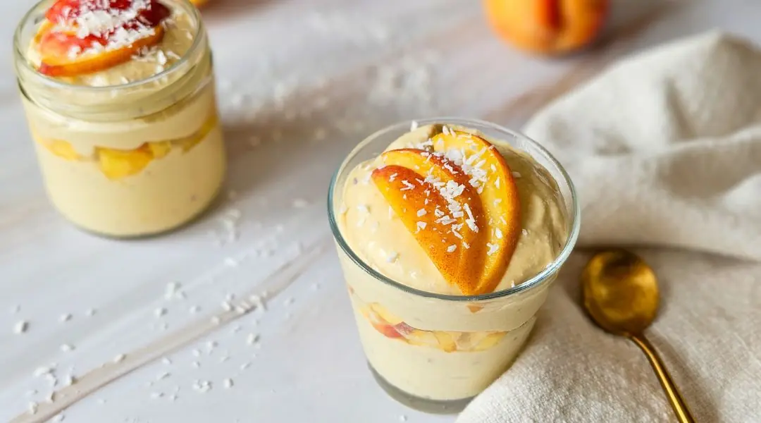 Mousse à la mangue  dans un verre, garni de tranches de fruit et noix de coco râpée