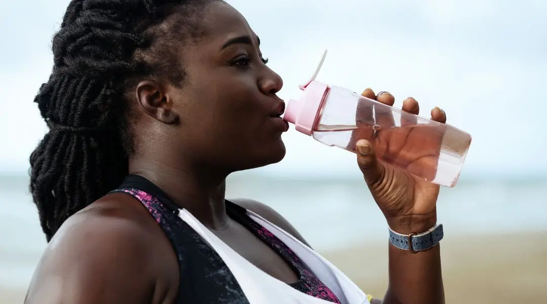 Femme s’hydratant avec une bouteille d’eau après l’exercice