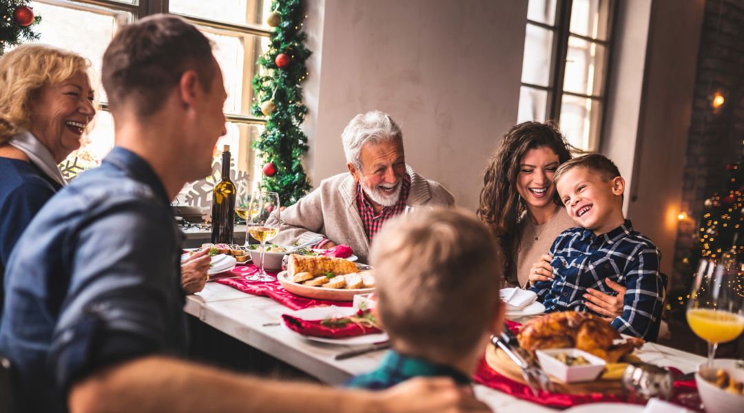 Une famille intergénérationnelle joyeuse partageant un repas de Noël, avec des décorations festives en arrière-plan