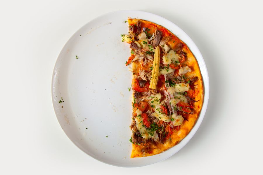 Half-eaten pizza on a white plate