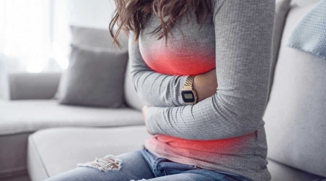 A person sitting on a couch with stomach pain.