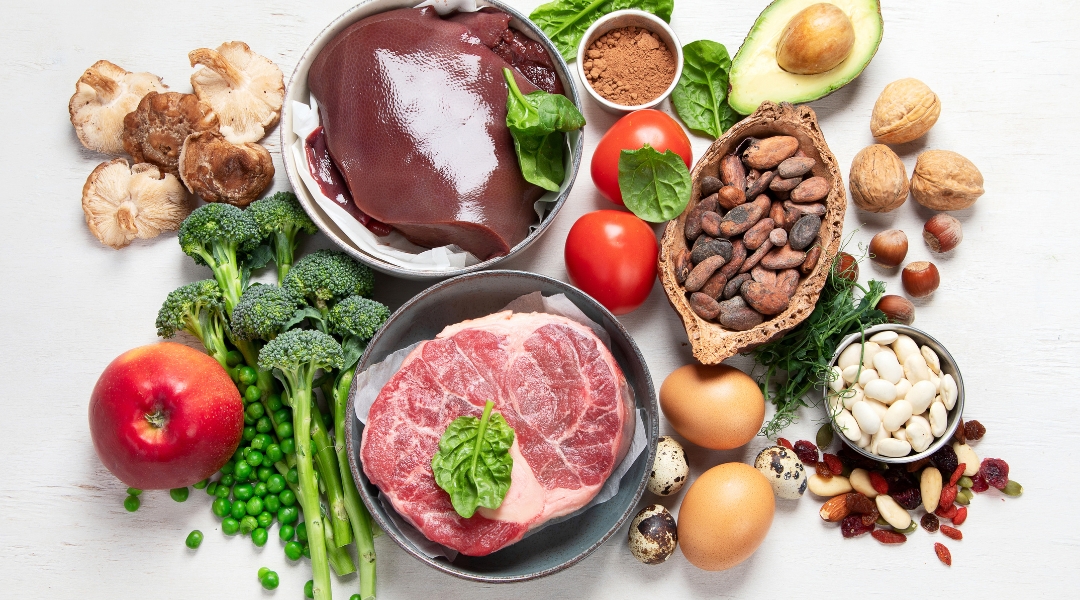 an assortment of foods including meat, vegetables and nuts rich in iron.