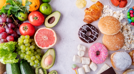 Une vue divisée de fruits et légumes sains à gauche, contrastant avec des aliments transformés comme des beignets et des hamburgers à droite.   A split view of healthy fruits and vegetables on the left, contrasted with processed junk foods like donuts and burgers on the right.