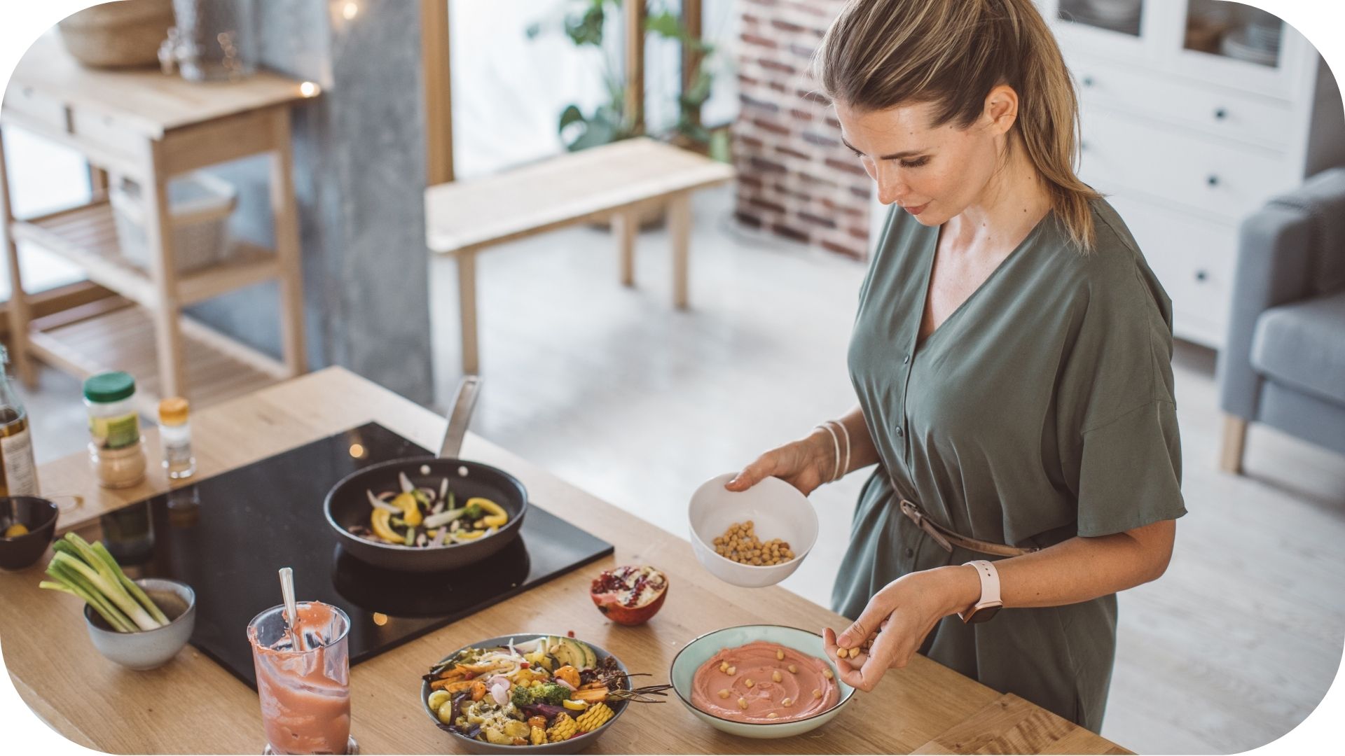 Femme préparant un repas dans une cuisine moderne, ajoutant des pois chiches à un bol de houmous ros