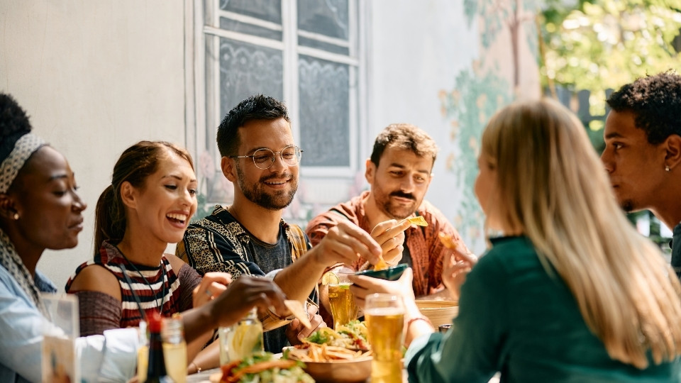 Un groupe d'amis partageant un repas dans un restaurant à Nepean, Ottawa, échangeant nourriture et boissons dans une ambiance décontractée et conviviale.