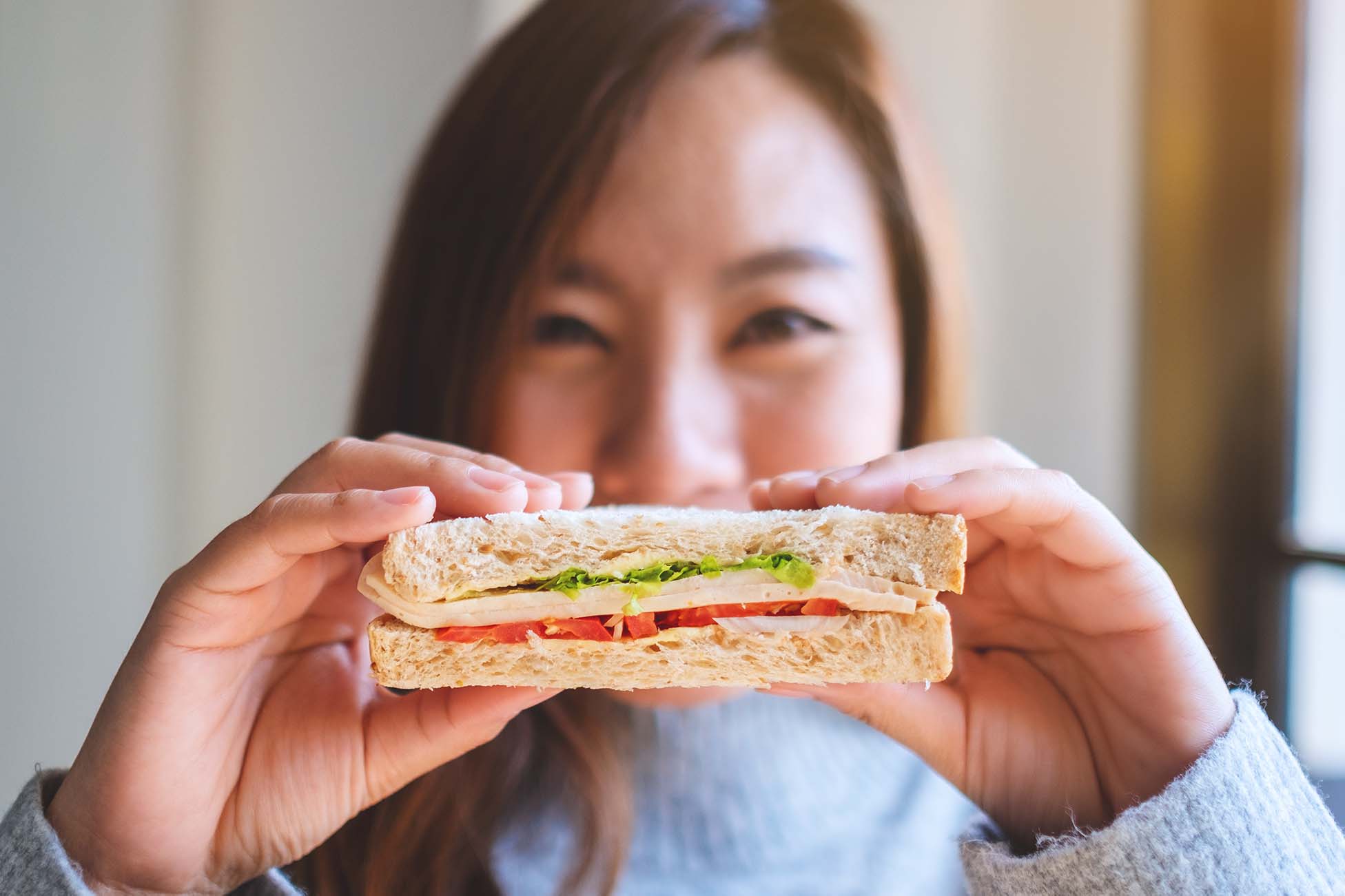 A smiling woman holding a sandwich - Une femme souriante tenant un sandwich