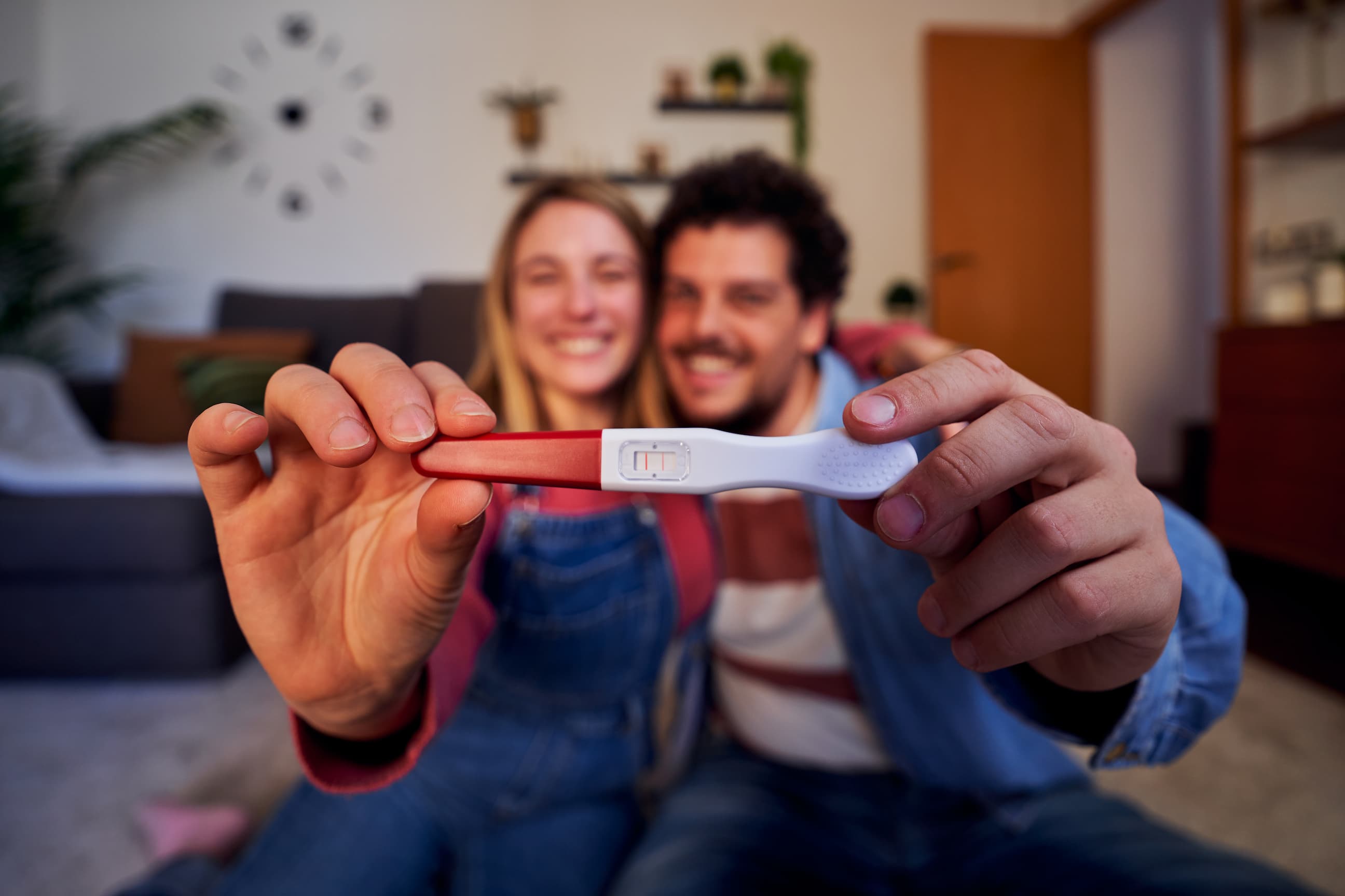 Couple heureux sourit en tenant un test de grossesse positif - Happy couple smiling and holding a positive pregnancy test