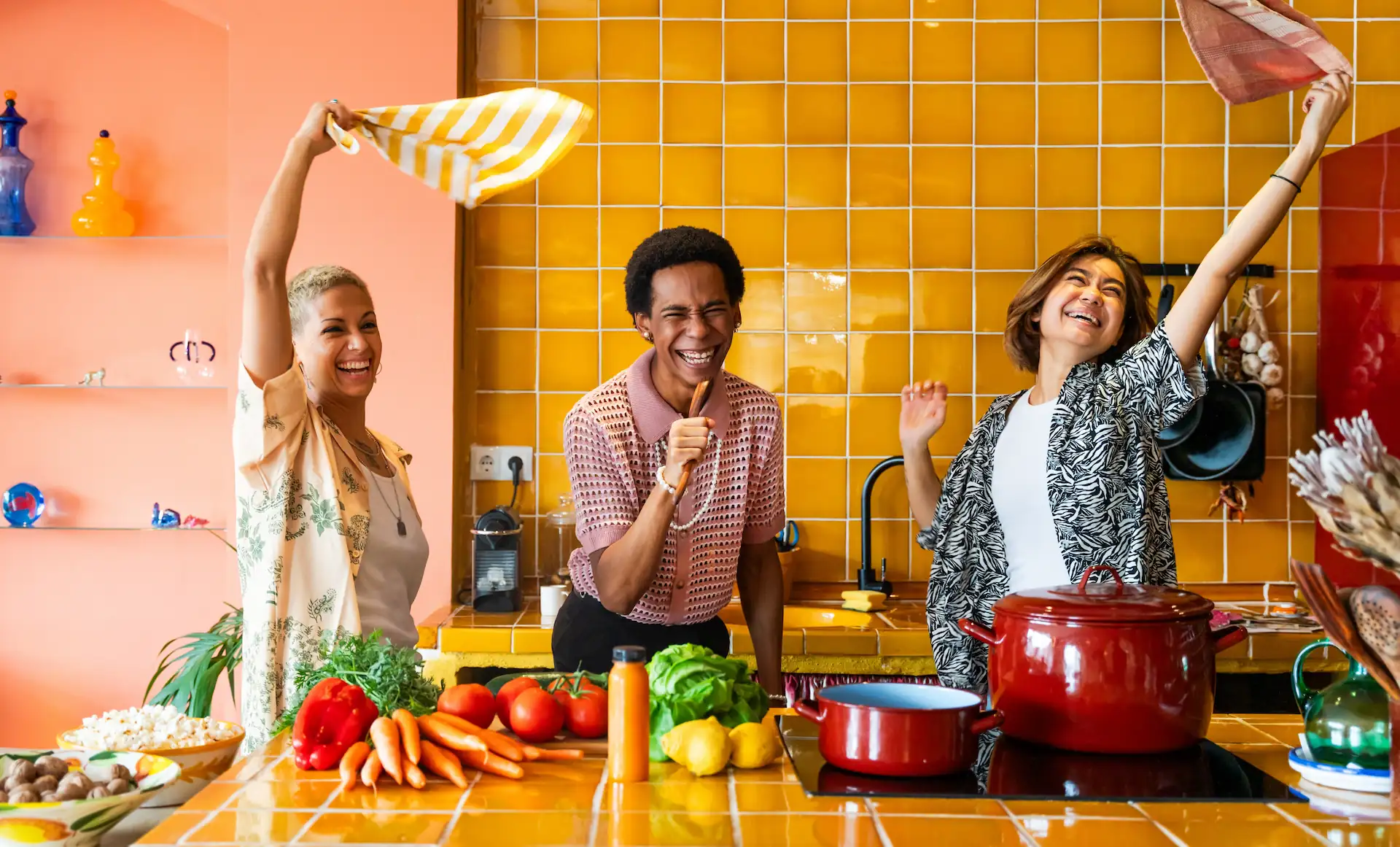 Trois amis souriants s’amusent ensemble dans une cuisine colorée - Three smiling friends have fun together in a colorful kitchen