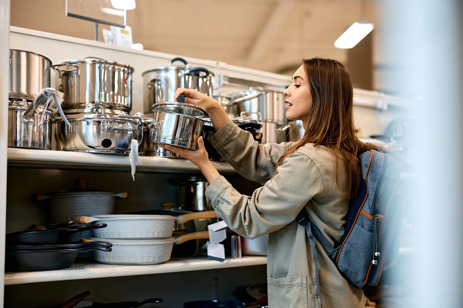 Femme choisissant une casserole en acier inoxydable dans un magasin de cuisine - Woman choosing a stainless steel pot in a kitchenware store