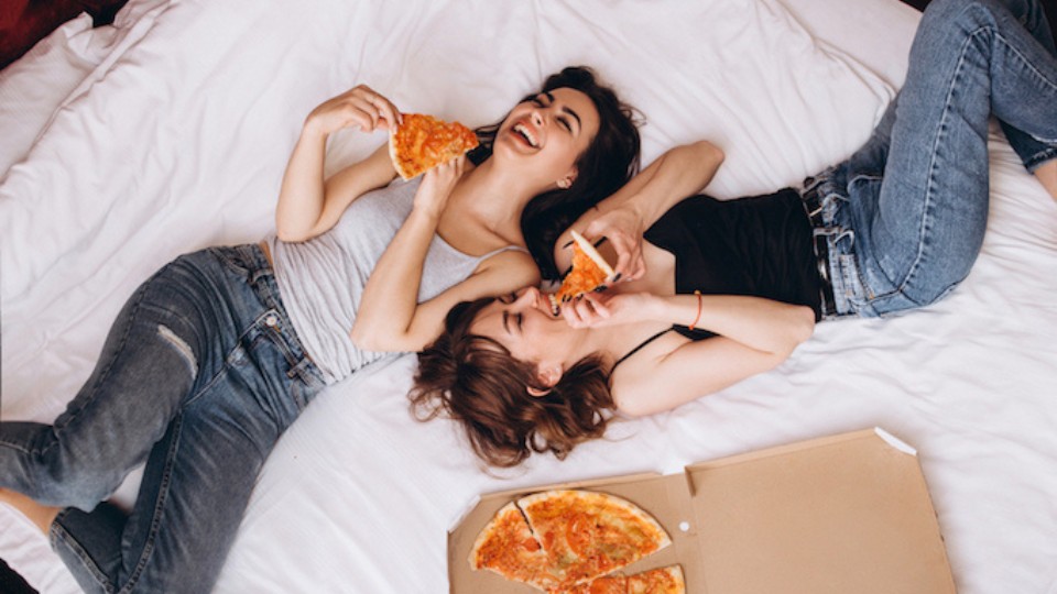 femmes qui mangent de la pizza sur le lit