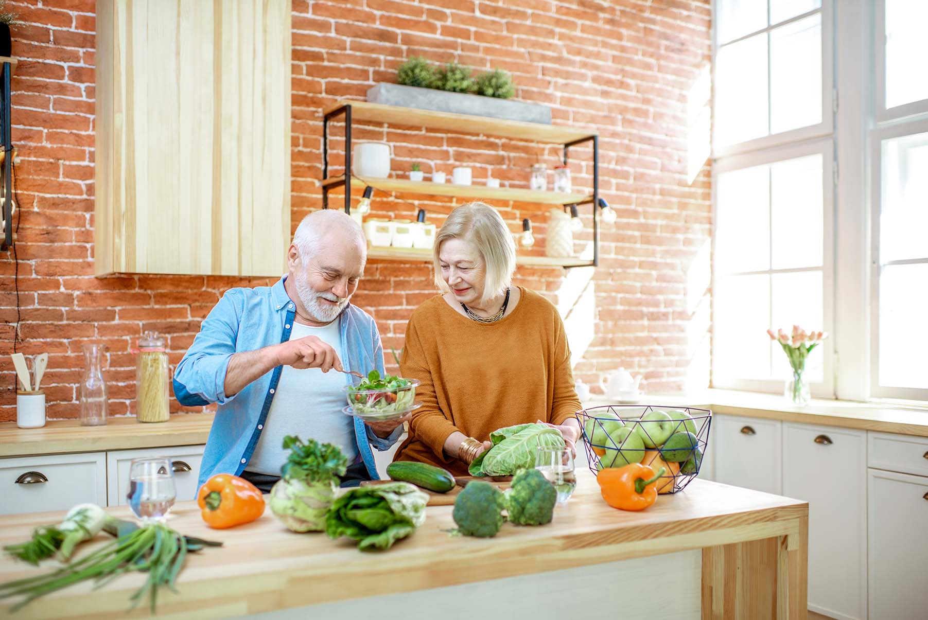 Deux jeunes femmes discutent lors d'une consultation en nutrition, assises à une table blanche dans une cuisine lumineuse. L'une d'elles explique avec des gestes, tandis que l'autre écoute attentivement.