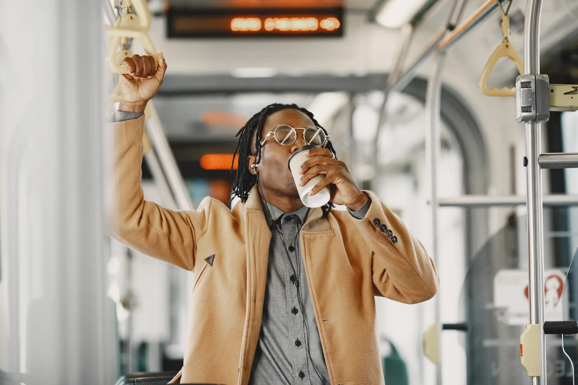 Homme tenant une poignée et buvant un café dans un autobus - Man holding a handle and drinking coffee on a bus