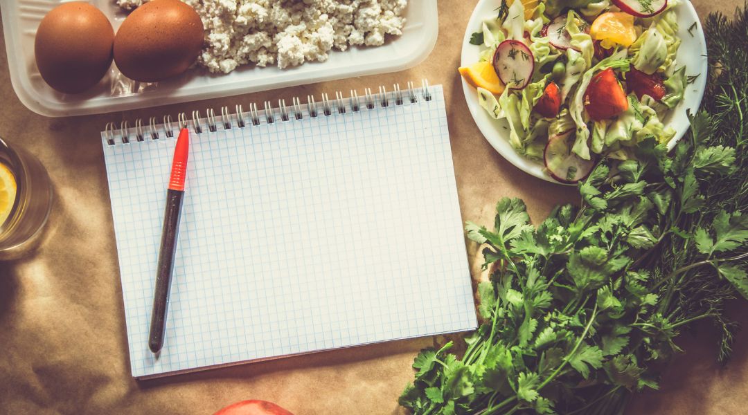 cahier avec crayon entouré de légumes