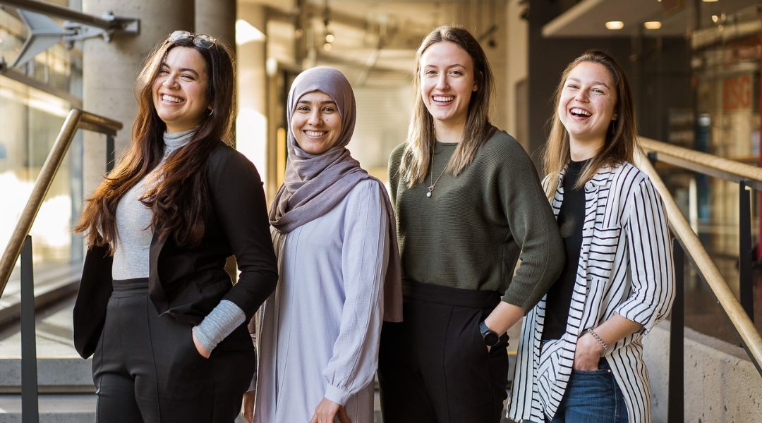 Quatre nutritionnistes diététistes d'ÉquipeNutrition souriant avec assurance, debout ensemble sur un escalier intérieur