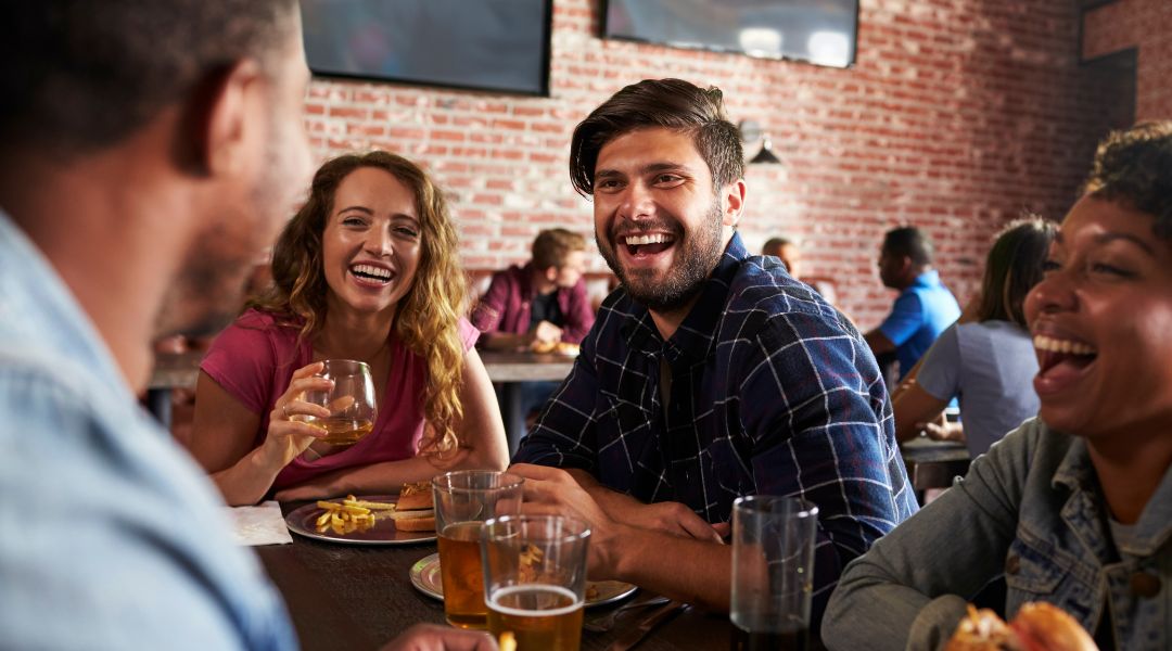 a group of people laughing and eating at a restaurant