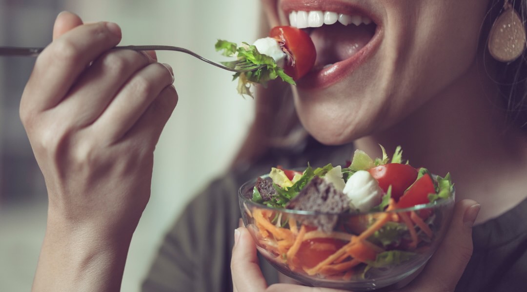 Une personne déguste une salade fraîche et colorée, composée de légumes croquants et d’ingrédients nutritifs.