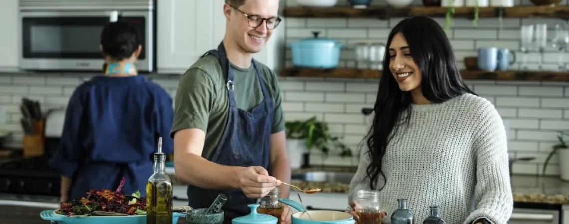 homme et femme souriants en cuisinant