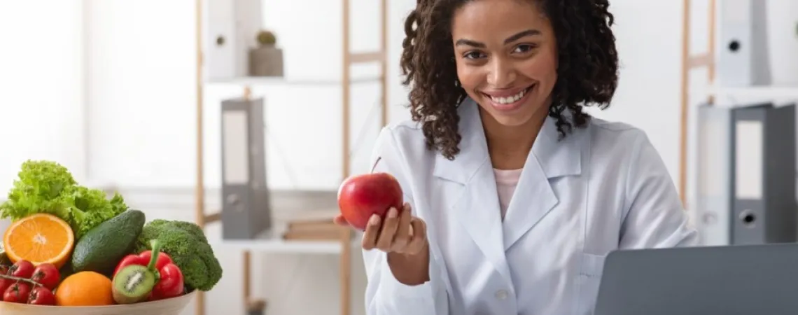 nutritionist-dietitian in her office presenting a fruit