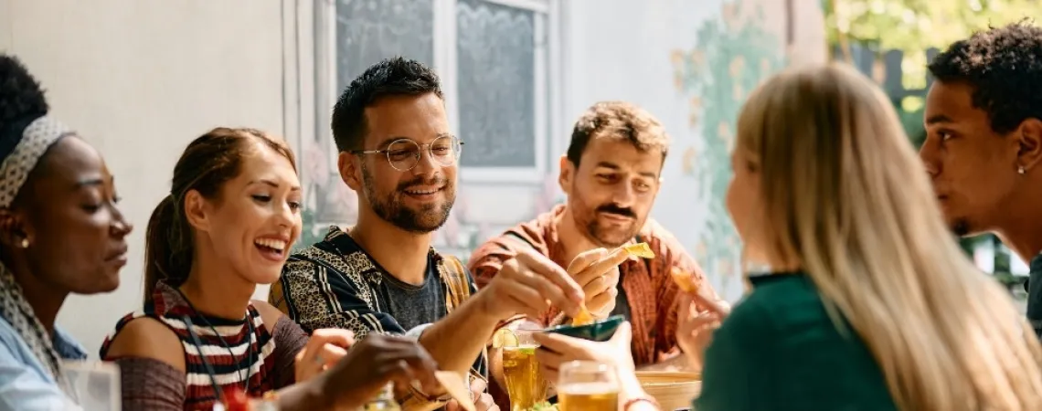 Un groupe d'amis partageant un repas dans un restaurant à Nepean, Ottawa, échangeant nourriture et boissons dans une ambiance décontractée et conviviale.