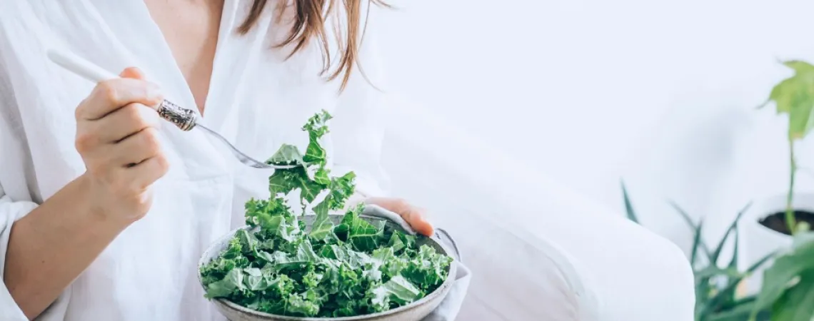 Fille habillée en blanc qui mange une salade de kale