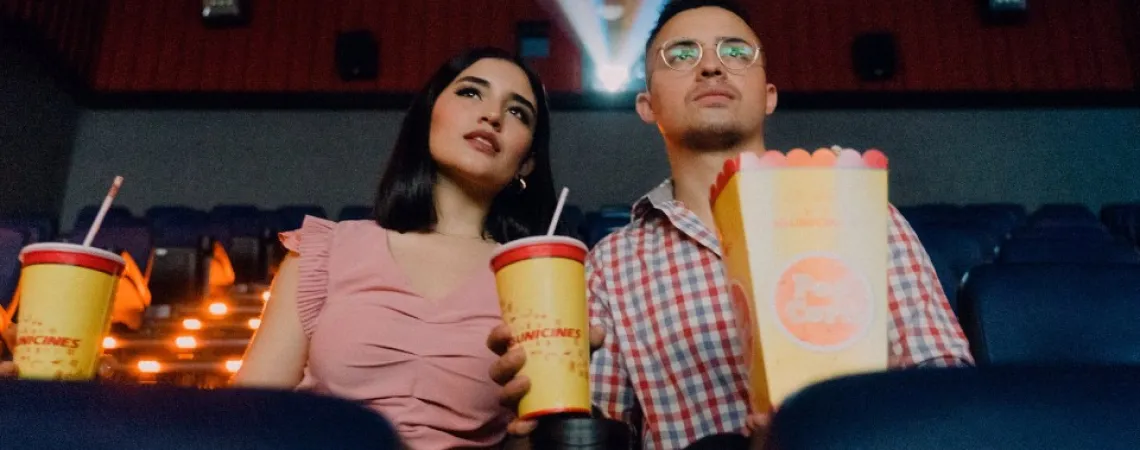 couple qui mange du popcorn avec des boissons gazeuses en écoutant un film au cinéma