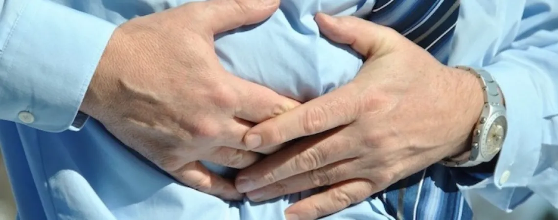 homme avec une chemise bleu qui a des douleurs abdominales