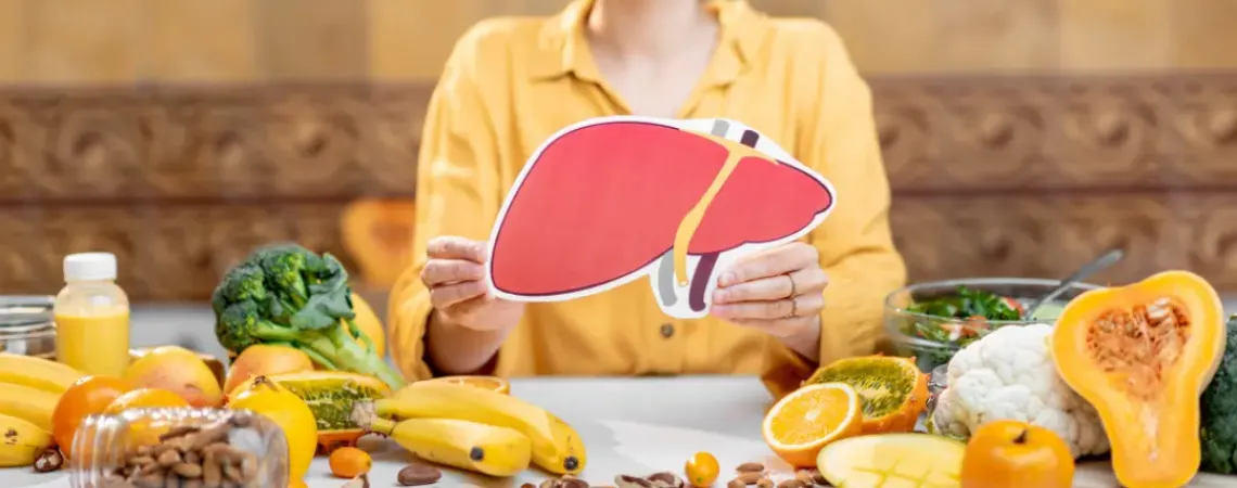 A person holding up a liver surrounded by fruits and vegetables. Nutritionnistes : acteurs clés de la  gestion de la stéatose hépatique métabolique