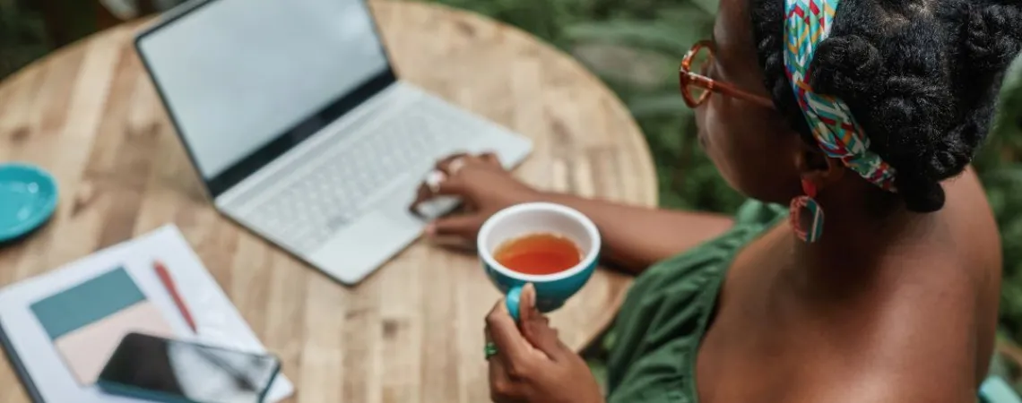 Femme buvant une tasse de thé devant son ordinateur