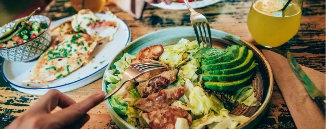 Chicken and avocado salad with forks digging in.