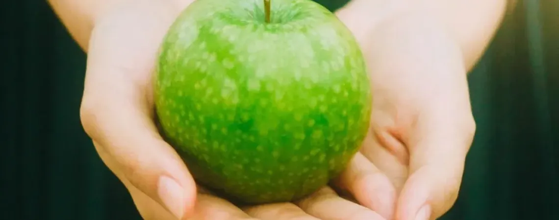 Une pomme verte sur la paume des mains