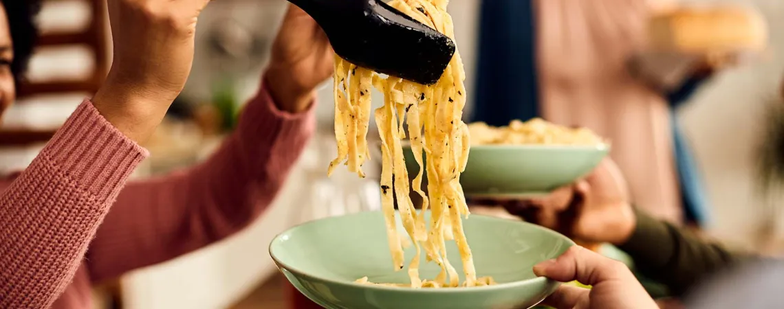 Gros plan d'une personne servant des pâtes fraîchement cuites - Close-up of a person serving freshly cooked pasta