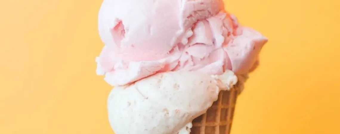 cornet de crème glacé rose et blanche sur fond orange