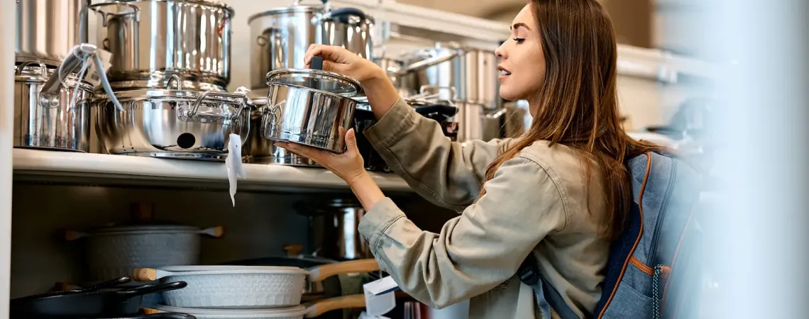 Femme choisissant une casserole en acier inoxydable dans un magasin de cuisine - Woman choosing a stainless steel pot in a kitchenware store