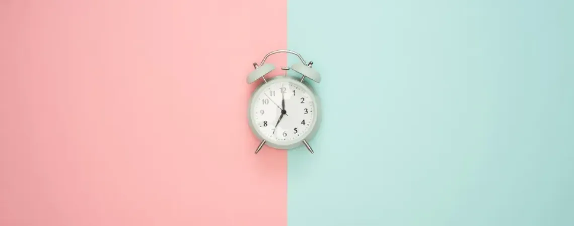horloge au centre d'un fond moitié rose et moitié turquoise