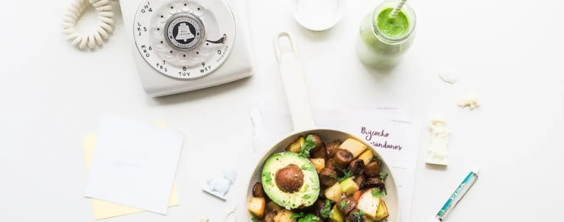 poêlée de légumes, smoothie et un téléphone sur une table blanche