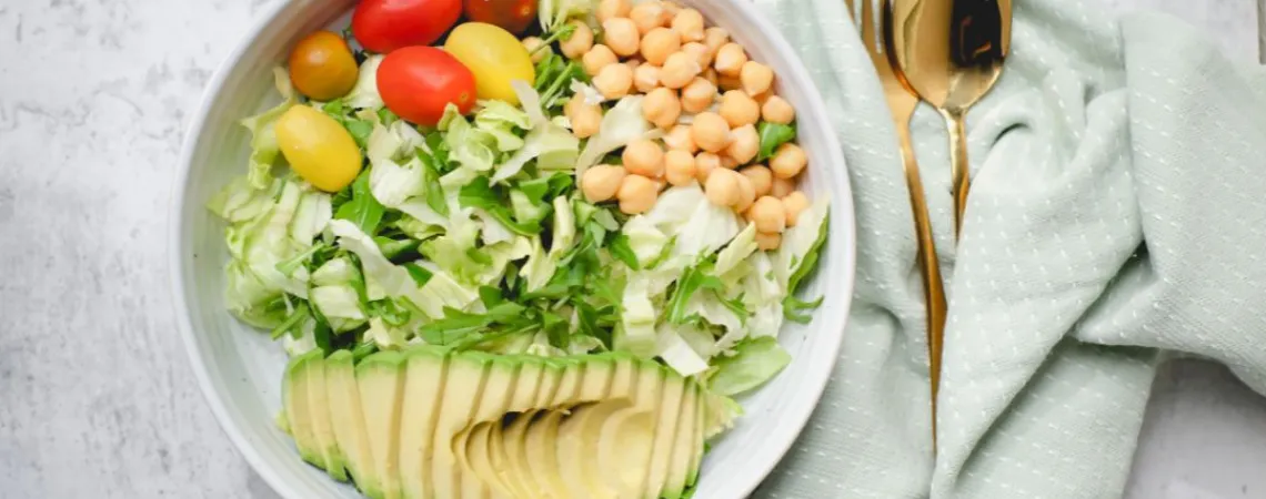 un bol de salade avec avocat, tomates et pois chiches