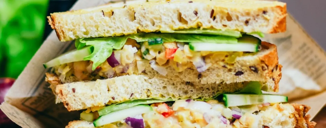 un sandwich coupé en deux dans un emballage papier