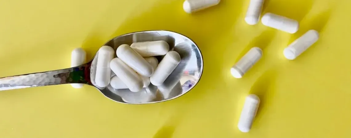 Suppléments dans une cuillère sur fond jaune