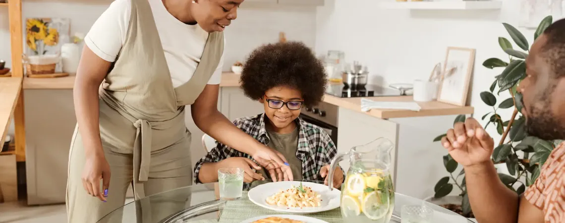 Famille souriante partageant un repas - Smiling family sharing a pasta meal