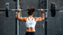 femme de dos musclée qui lève un haltère