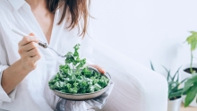 Fille habillée en blanc qui mange une salade de kale