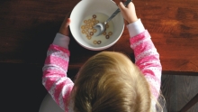 Enfant habillée en rose mangeant un bol de céréales avec du lait