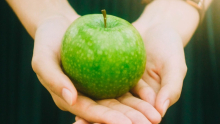 Une pomme verte sur la paume des mains